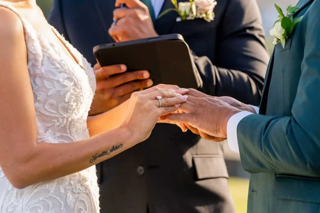 Close-up of bride and groom exchanging wedding rings during outdoor ceremony in San Diego