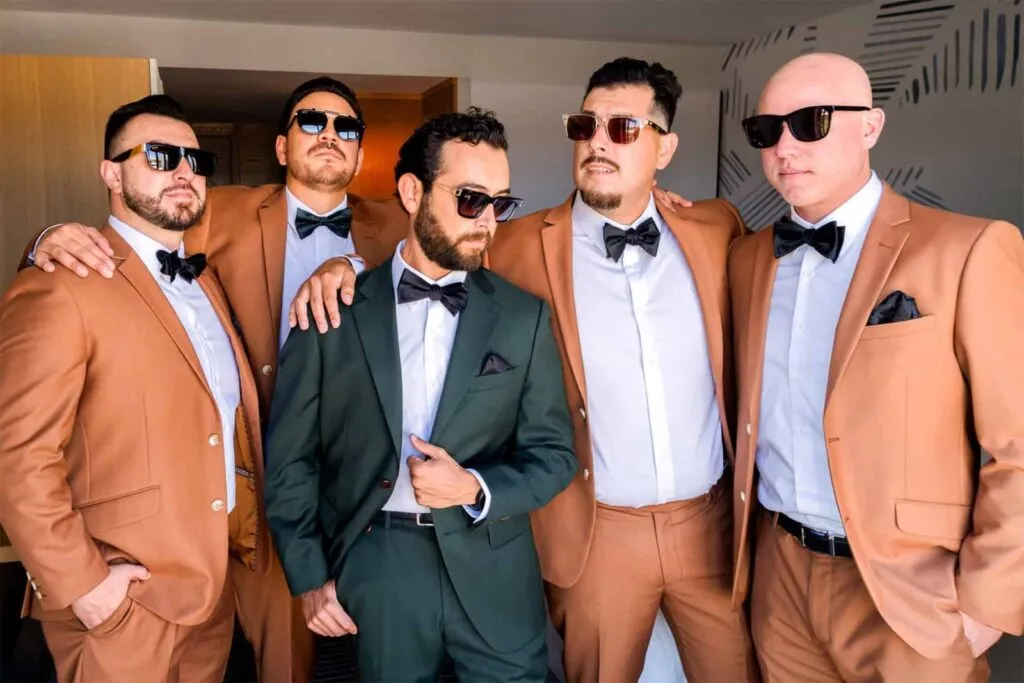 Modern groomsmen in brown suits and groom in green tux ready for San Diego wedding day