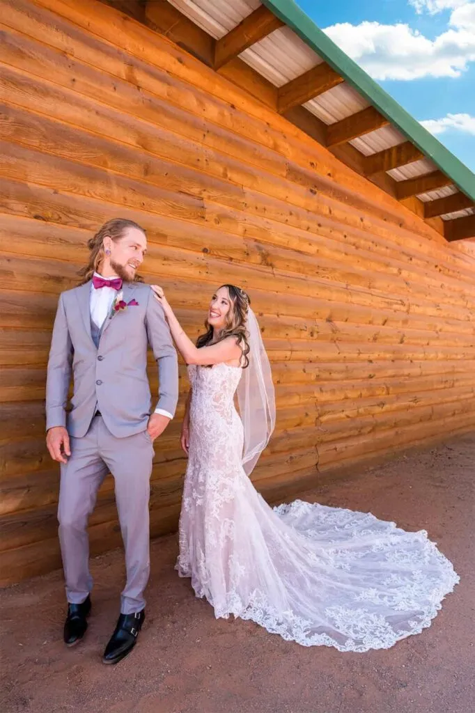 Bride surprises groom during first look outside a rustic log cabin at their wedding