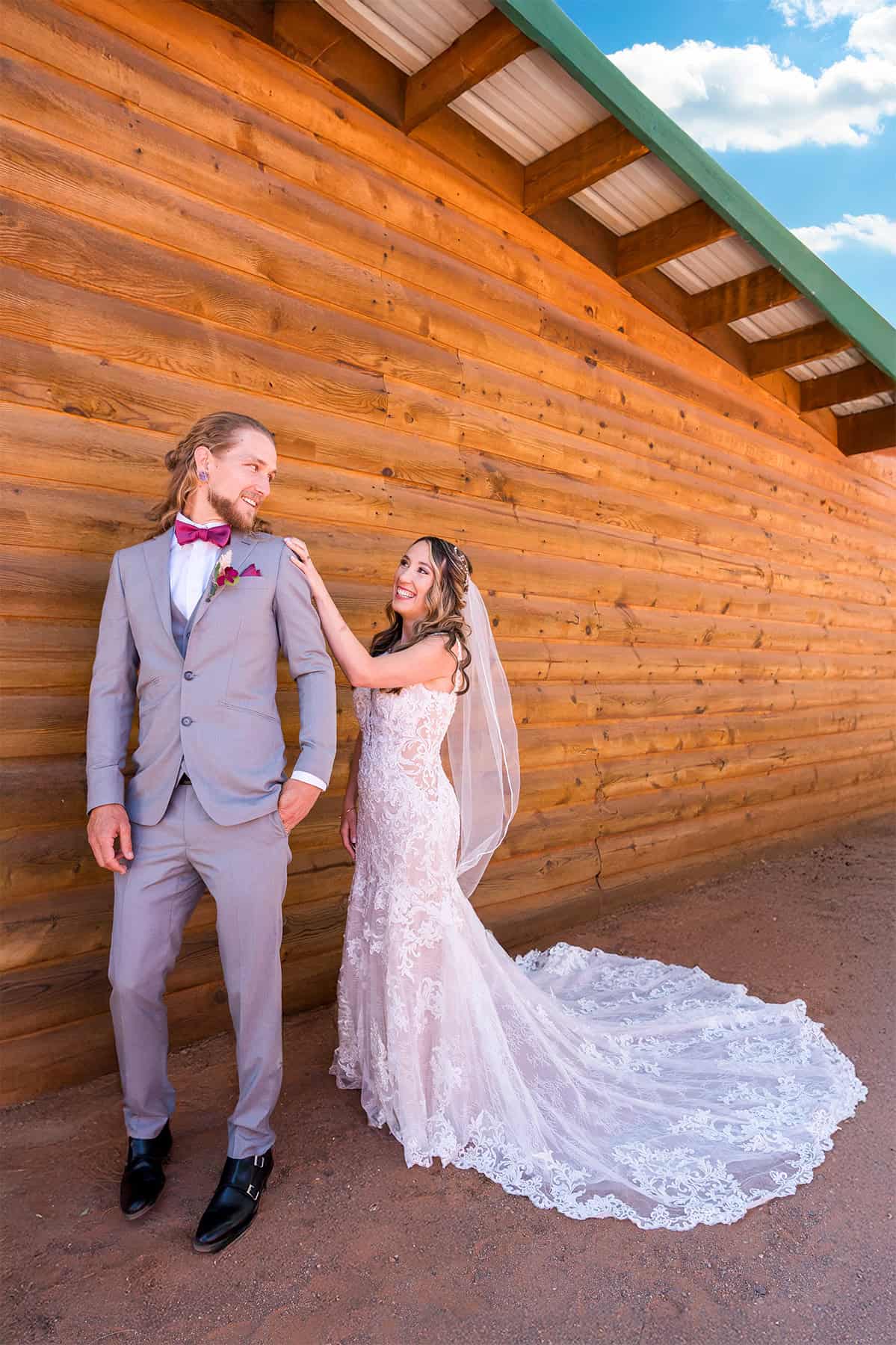 rustic-first-look-log-cabin-wedding Bride surprises groom during first look outside a rustic log cabin at their wedding