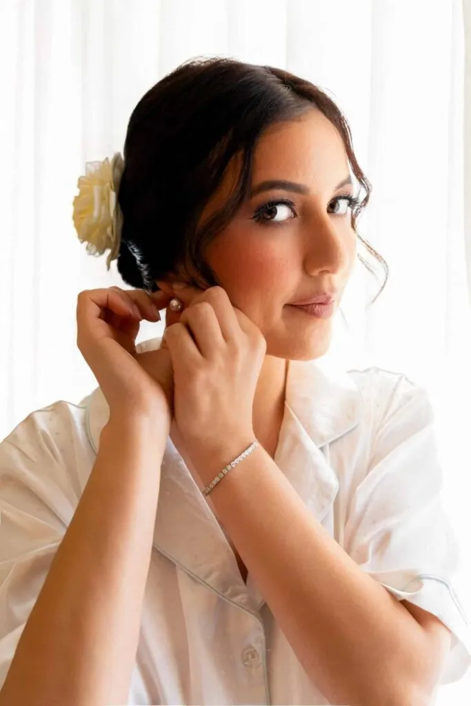 Elegant bride adjusting her earrings before wedding ceremony in San Diego