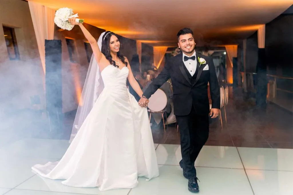 Bride and groom making a grand entrance with bouquet raised at San Diego wedding reception