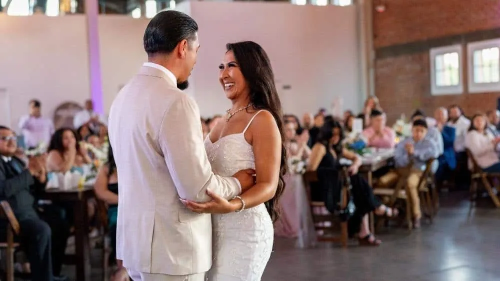 Bride and groom share a joyful first dance at their wedding reception surrounded by guests in a San Diego venue.