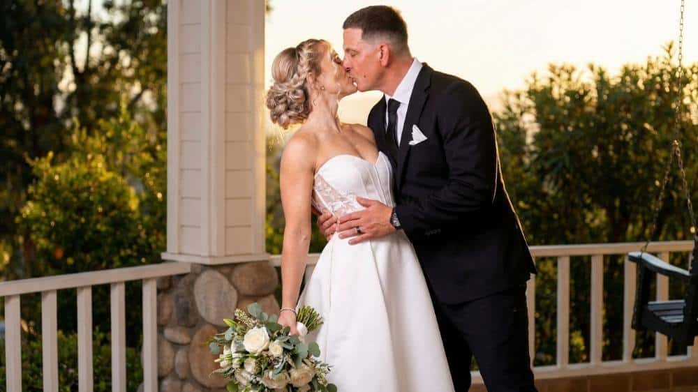 Romantic wedding portrait of a couple kissing during golden hour on a porch