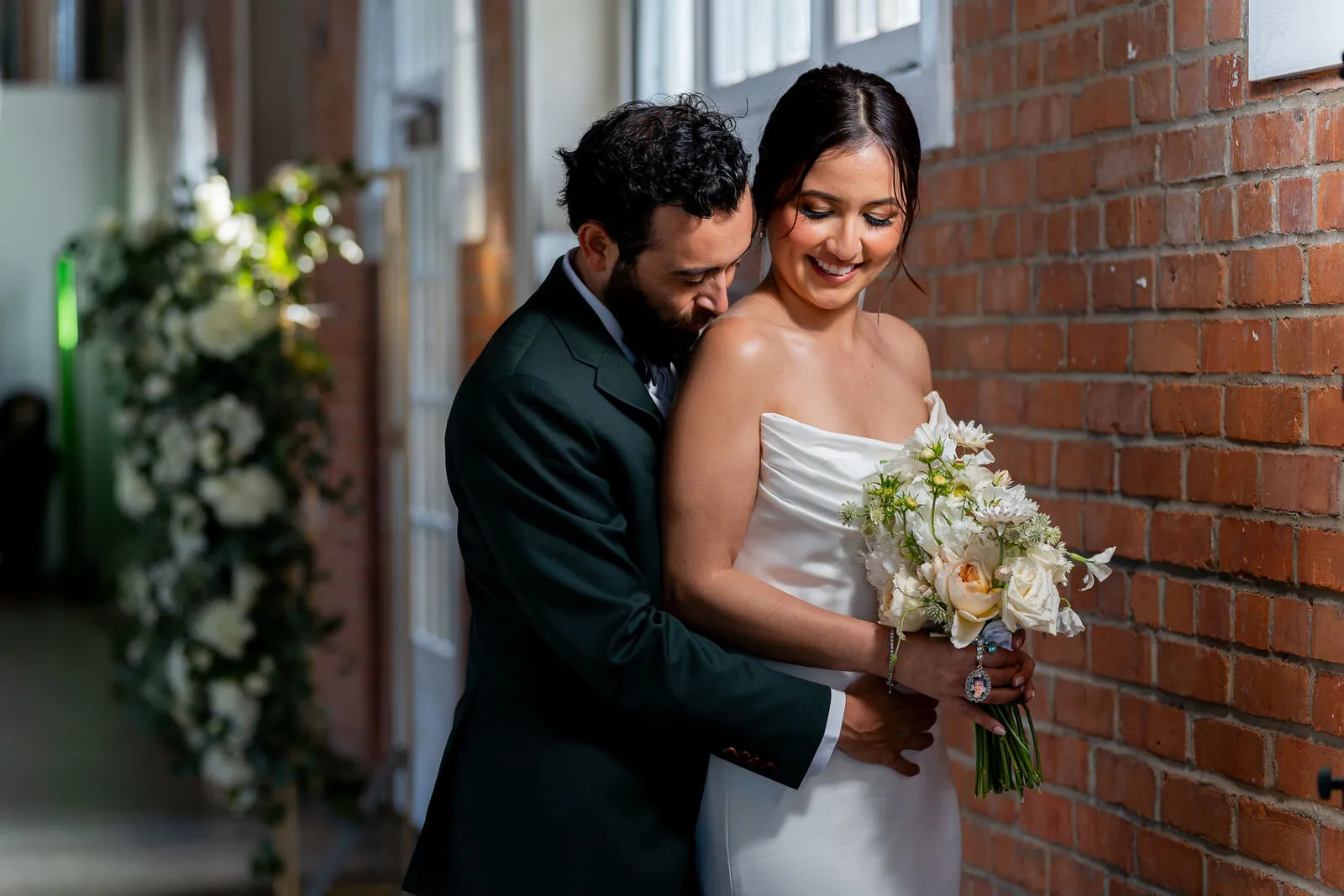 Bride and groom share an intimate moment against a red brick wall during their San Diego wedding day portrait session.