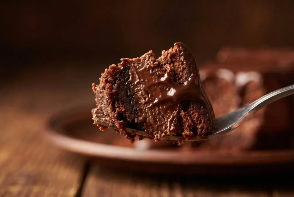 Fork holding a slice of rich chocolate cake with moist crumb texture, perfect for food product photography and bakery marketing.