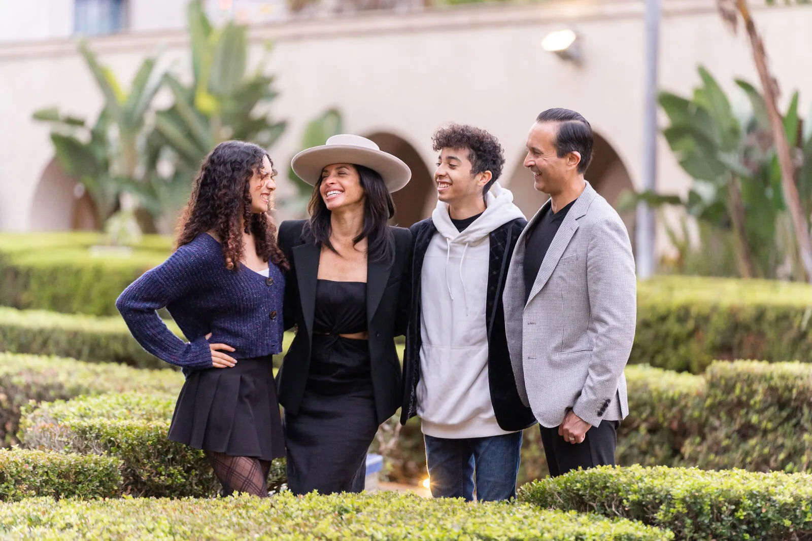 Family photography of four people smiling together in a lush garden setting, representing authentic family photography in San Diego.